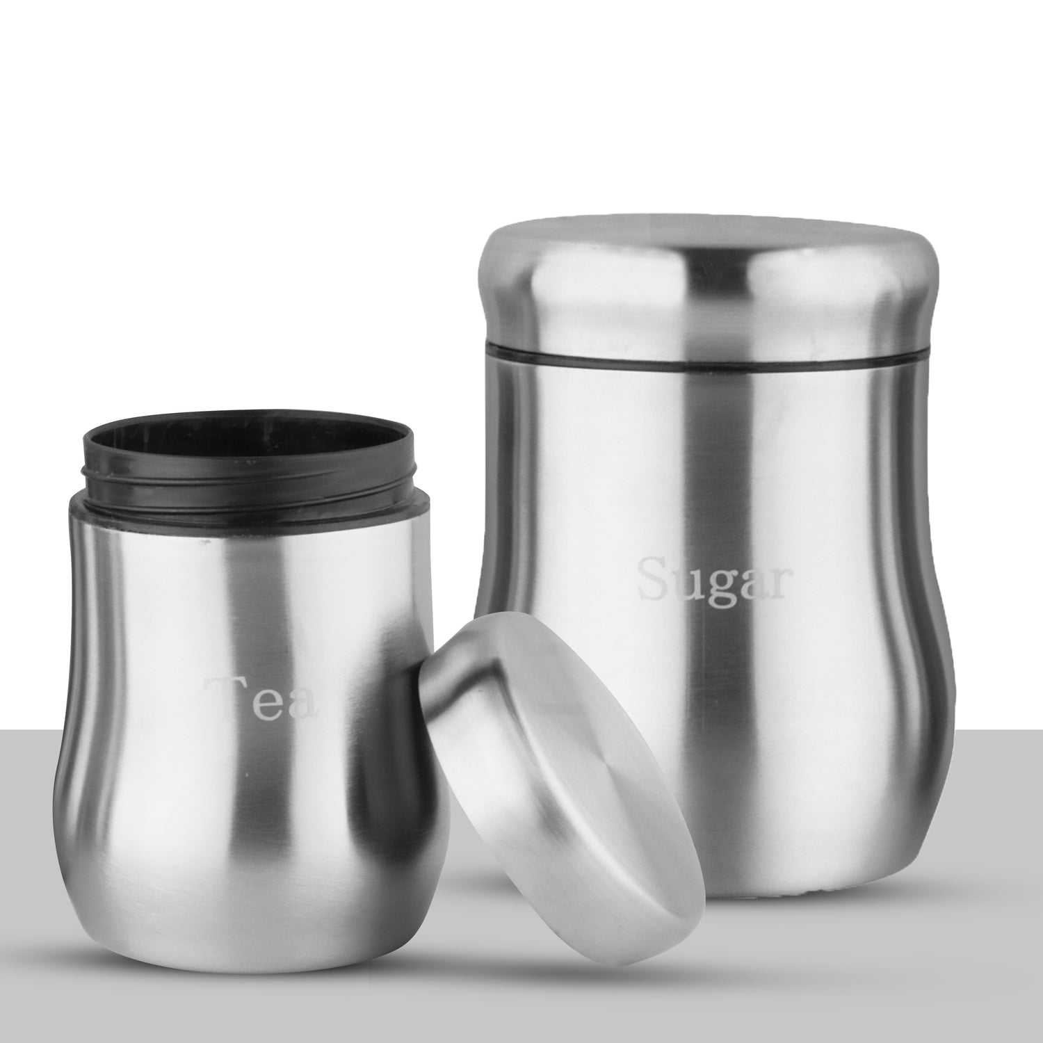 Two-piece stainless steel canister set labelled Tea and Sugar, with the Tea jar opened and its lid resting against it