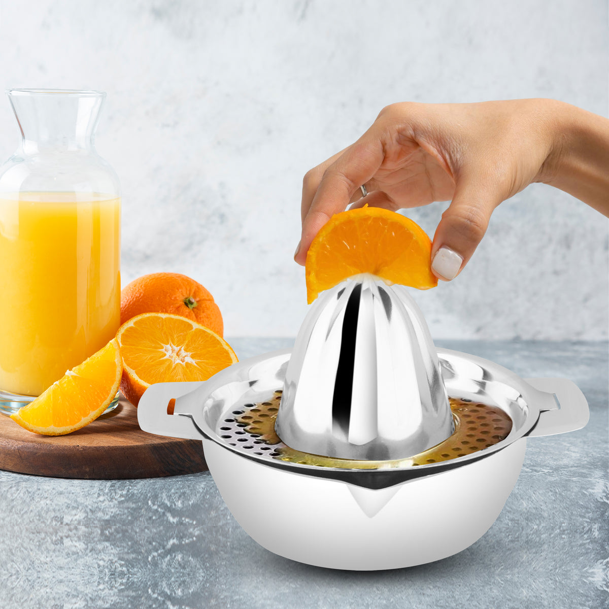 "Hand squeezing fresh orange juice using Garuda stainless steel citrus juicer – perfect for lemons, oranges, and limes – premium quality manual juicer for effortless extraction."